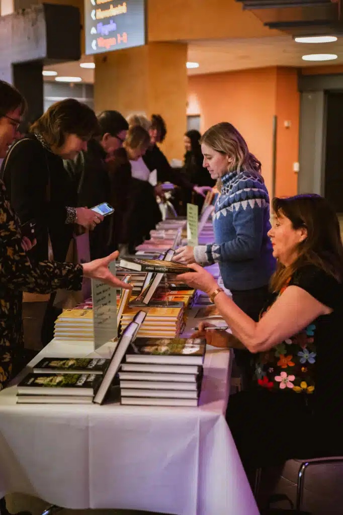 Två kvinnor säljer böcker från ett bord till flera personer