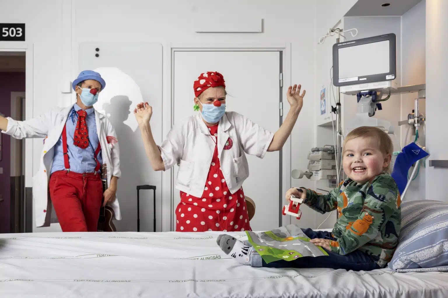 Clowner och ett litet barn på sjukhus som skrattar